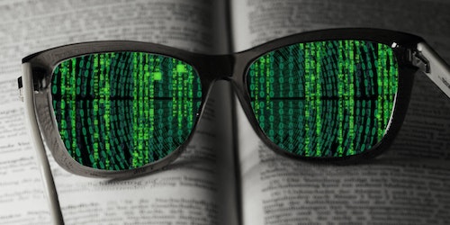 A pair of glasses lying on a book, through the lenses of which you can see lines of code instead of written text