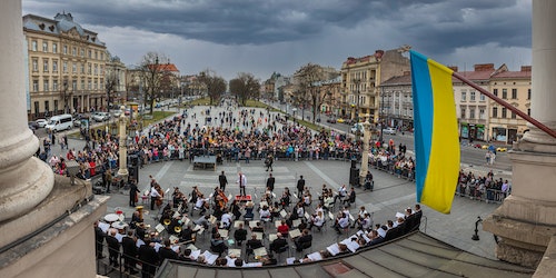The Ukrainian flag flies above a concert orchestra playing outdoors in Lviv