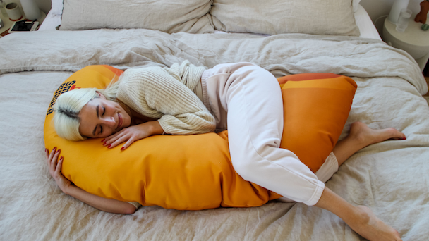 woman hugging a macaroni shaped pillow